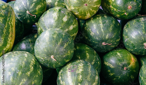 Bild auf Leinwand A dense pile of ripe green striped watermelons stacked closely together at a mar