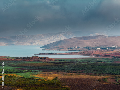 Tableau sur toile Coastal plain beneath cloudy mountain ridge