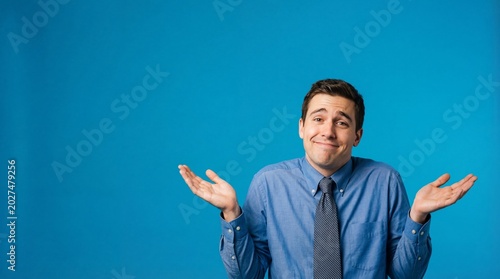 caucasian man in shirt and tie shrugging his shoulders with confused expression. concept of uncertainty, doubt. business professional, blue background, banner, website header, copyspace.
