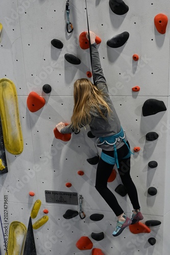 Young climber scaling a colorful indoor rock wall with confidence, focus, and determination during an exciting climbing gym training session