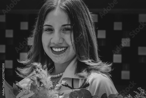 A young woman smiles radiantly while holding a bouquet of flowers
