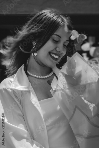 A young woman laughs happily while holding a bouquet of flowers
