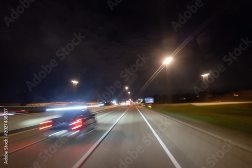 Night driving point of view on an asphalt highway with car streaks