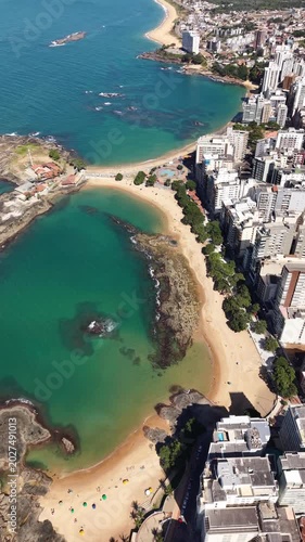 Panoramic aerial drone view of Guarapari, Espírito Santo, Brazil, with tropical beaches, turquoise Atlantic Ocean, urban coastline, rocky shores and mountains in the background.