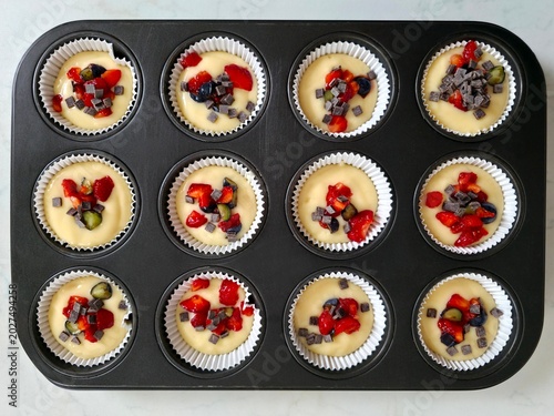 Raw muffins decorated with fresh spring fruit and prepared and ready to bake