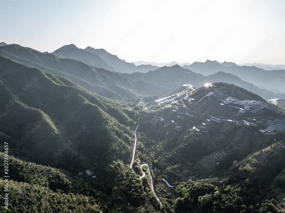 Fototapeta premium Winding road through green mountains and valleys under bright sunlight
