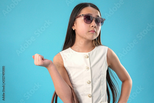 Posing young asian girl wearing sunglasses looking aside thoughtfully