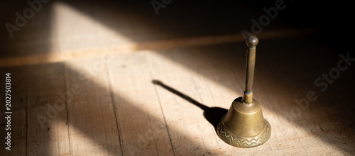 Photos Catholic altar bell with shadow on wooden surface