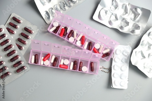 Fotografia Pill organizers with medications and empty blisters on light grey background, fl