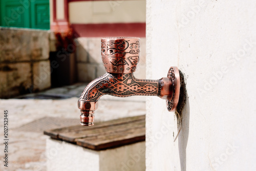 Schilderij op canvas Close up of an intricately patterned copper faucet designed for ritual washing w