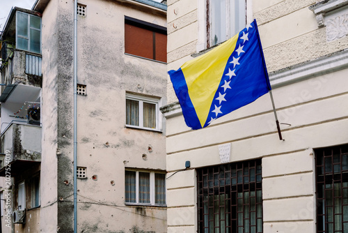 Fotografie Bosnian facades bear war scars; the flag flies, symbolizing resilience amidst hi