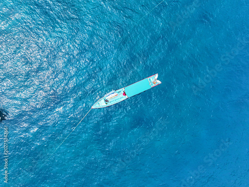 фотографія AERIAL TOP DOWN: Turquoise surf taxi floating over deep blue water in Mentawai Islands