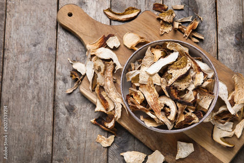 Photos Bowl with tasty dried mushrooms on wooden background