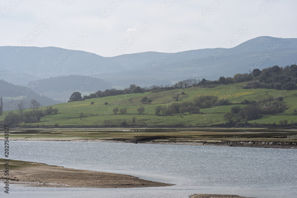 Fototapeta premium Calm Estuary with Green Hills and Distant Mountains