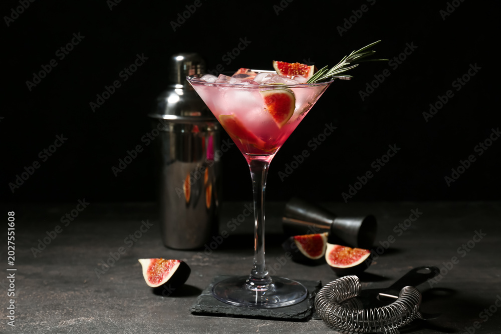 Obraz premium Glass of tasty fig lemonade and bartender tools on black grunge background, closeup
