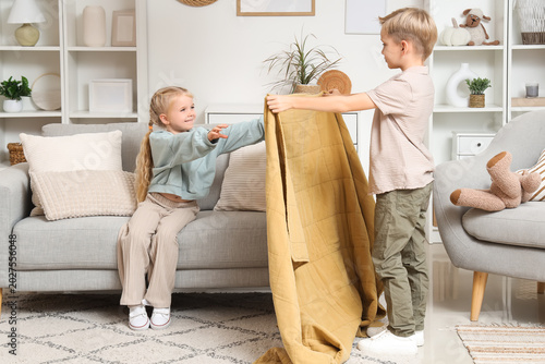 Little boy giving plaid to his sister at home