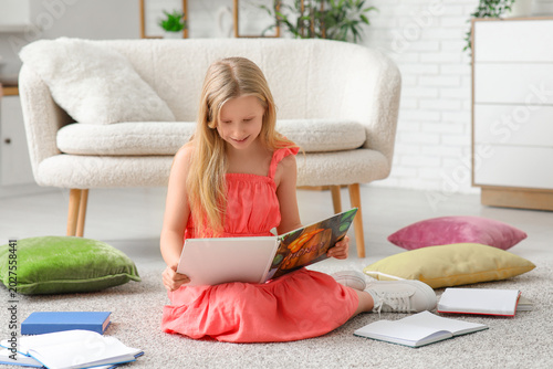 Cute little girl reading bo...