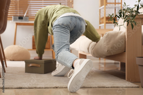 Young woman tripping over carpet at home. Trauma concept