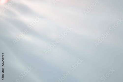 Bright abstract background with a soft light leak and gentle diagonal waves in pale tones