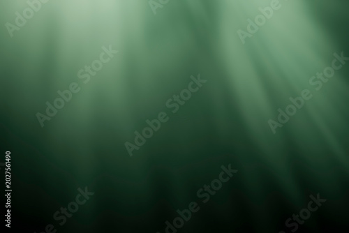 Soft cinematic green light beams illuminating a dark atmospheric background with smooth volumetric glowing effects