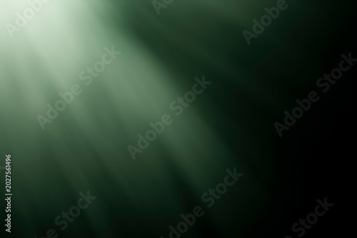 Abstract diagonal green light rays shining through a dark background
