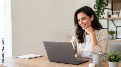 Smiling young woman using laptop and wireless earbuds with copy space