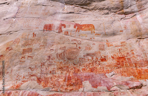 Fényképezés Ancient pictographs depicting animals in red hue cover the rocky surface, showcasing intricate patterns