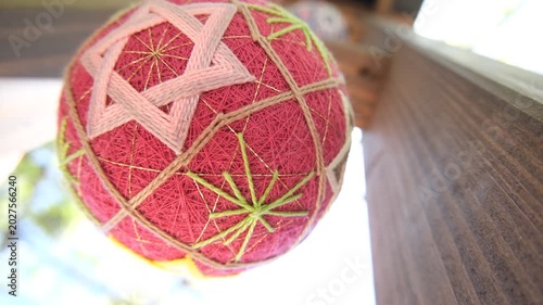 Hanging Japanese temari ball gently swinging and rotating, silent traditional craft footage