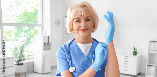 Female doctor putting on medical gloves at hospital