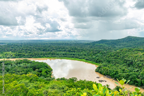 Foto A winding river whose brown waters contrast with the vibrant green jungle, surrounded by a cloudy sky in Guaviare, Colombia