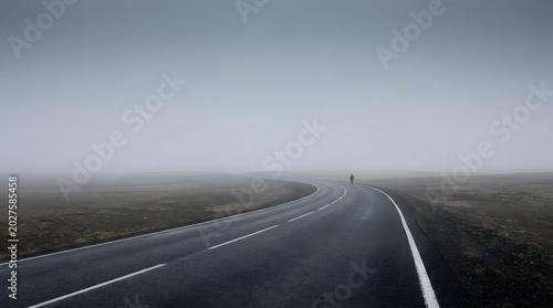 Empty Curving Road Surrounded by Vast Open Landscape Under Foggy Sky