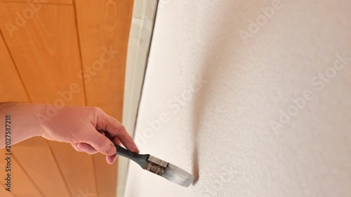 Wall renovation and painting. Movement of a paintbrush in white paint on a textured wall.4k footage