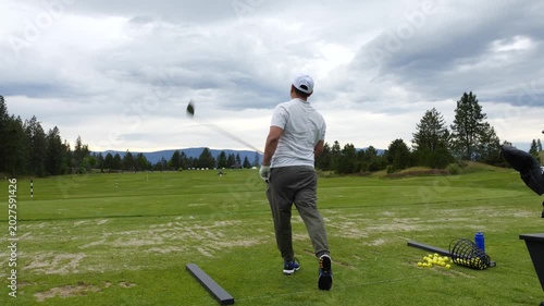 Asian man hits a driver on a grass driving range