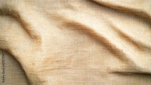 Abstract background of natural beige woven burlap fabric with elegant folds and soft shadows for photography studio backdrops