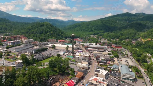 Aerial landscape of Gatlinburg city center with busy tourist streets, main Parkway filled with shops and restaurants, and scenic Smoky Mountains in the background.