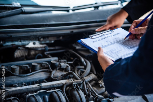 Close up Car Mechanic man hands repairing car auto repair shop. Close up hand man check engine oil level Locate dipstick, wipe clean, check dipstick level before fill up engine oil. open vehicle