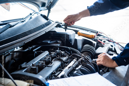Close up Car Mechanic man hands repairing car auto repair shop. Close up hand man check engine oil level Locate dipstick, wipe clean, check dipstick level before fill up engine oil. open vehicle