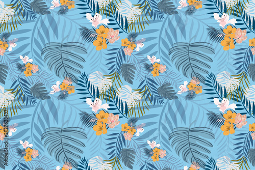 фотографія Elegant seamless tropical floral pattern with layered palm leaves, exotic flowers, and botanical foliage on a soft blue background