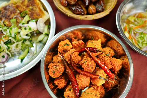 Crispy fried chicken bites topped with dried chili peppers served alongside fresh salad and traditional side dishes. Authentic halal street food for Ramadan, iftar and festive dining themes.