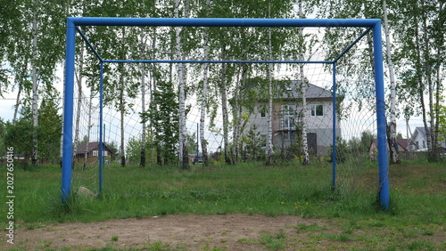 Cuadro en lienzo Blue metal soccer goal with net on grassy, patchy dirt field by birch trees and