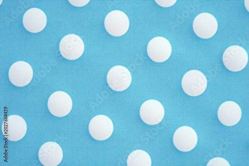light blue background covered with raised white polka dots in a playful, cheerful repeating pattern