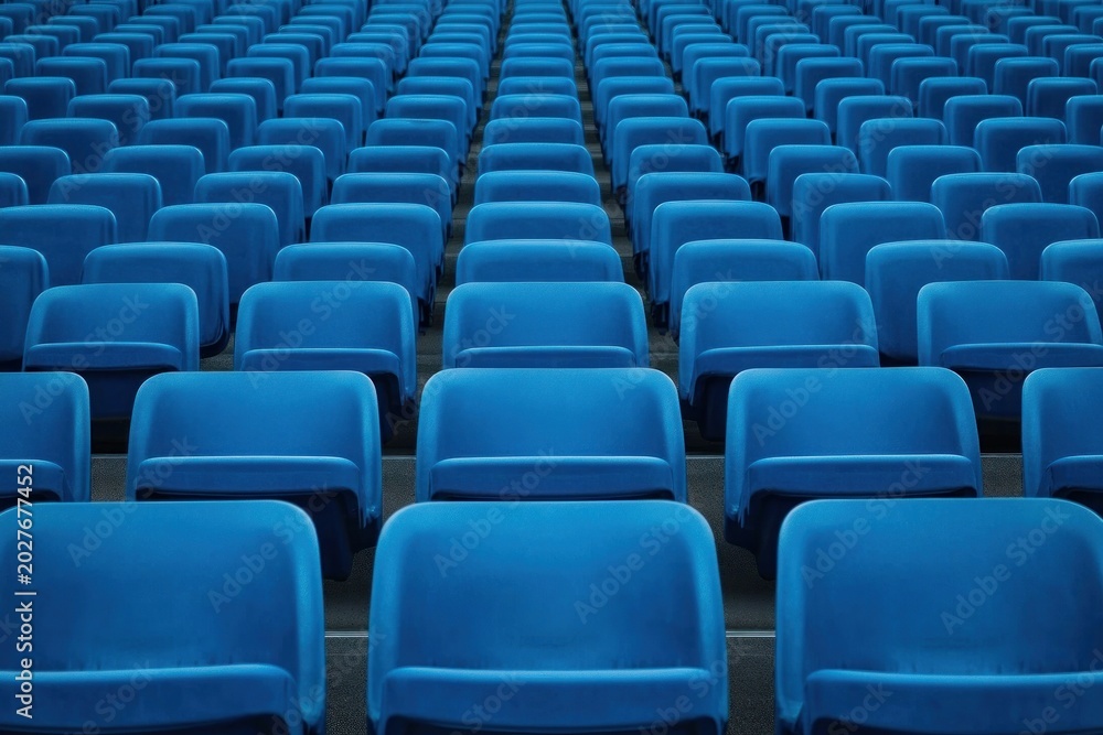 Fototapeta premium Endless rows of empty blue stadium seats in perfect symmetry and repeating pattern, conveying quiet stillness and calm emptiness