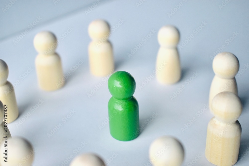 Obraz premium A green wooden peg placed in the center of a circular arrangement of natural wood pegs.