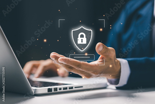 Businessman using laptop with virtual security shield and password protection interface, representing cybersecurity, data privacy, secure login and online protection technology.