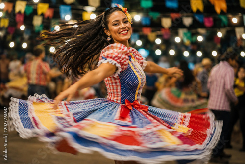 Joyful Brazilian woman dancing in traditional quadrille dress at Festa Junina celebration.