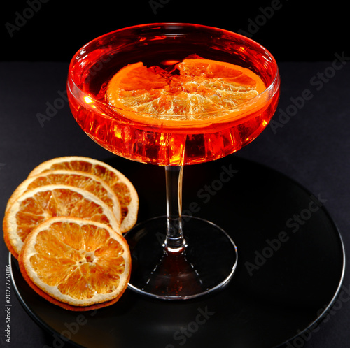 Foto Vibrant red cocktail with ice cubes in a coupe glass, accompanied by dried orang