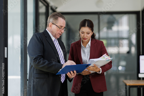 Fotografie Mature business professional mentoring asian female junior executive, discussing