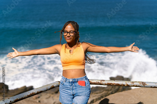 Schilderij op canvas Young woman enjoying freedom stretching arms by ocean