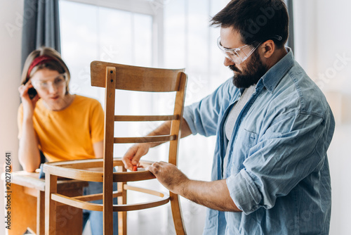 Focused man and woman restoring old wooden chair together