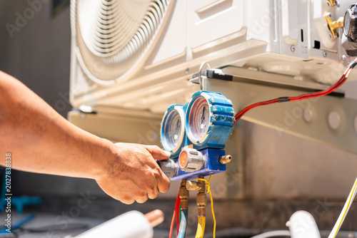 Foto Technician using manifold gauge to check air conditioner refrigerant pressure  i